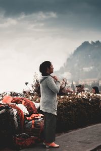 Rear view of woman standing on rock against sky