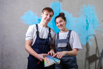 Portrait of smiling couple standing against wall