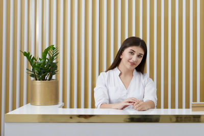 Portrait of young woman sitting on table