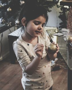 Close-up of smiling girl holding bauble at home