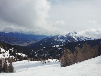 Scenic view of snow covered mountains against cloudy sky