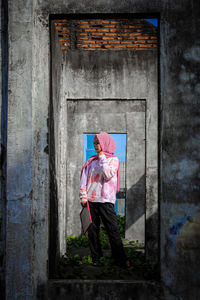Rear view of woman standing by pink building