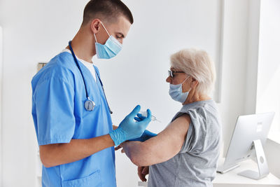 Doctor wearing mask vaccinating patient