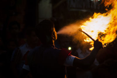 Rear view of man performing fire arts at night