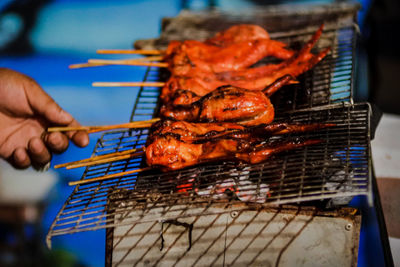 Person holding meat on barbecue grill