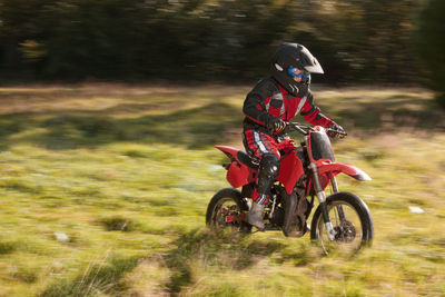 12 year old boy riding his motocross motorcycle through field