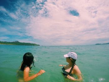 Women swimming in lake against sky during summer