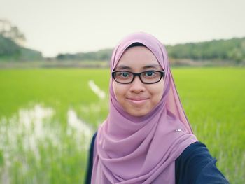 Close-up portrait of woman wearing hijab against rice paddy