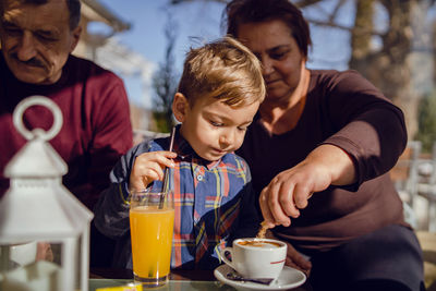 Boy looking at grandmother making coffee on table