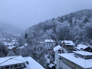 Snow covered buildings in town against sky