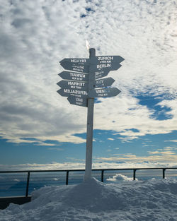 Information sign on snow covered road against sky