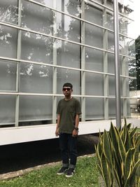 Full length of young man standing against glass building