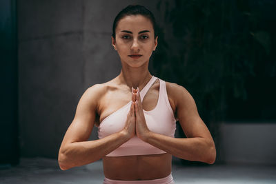 Portrait of woman with hands clasped exercising at gym