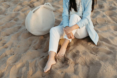 Low section of woman sitting on beach