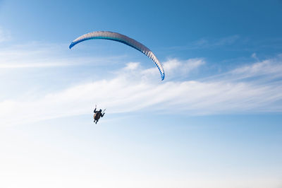 Low angle view of person paragliding against sky