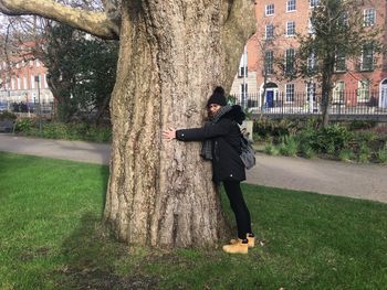 Full length of man standing by tree trunk