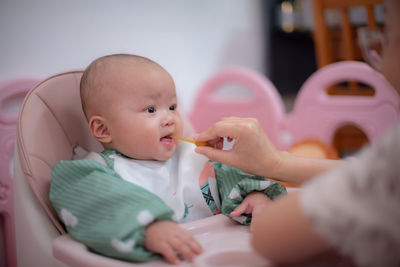 Portrait of cute baby girl eating food at home