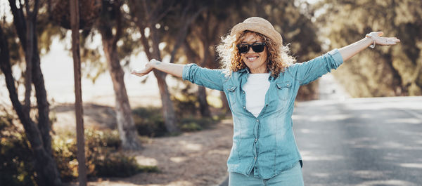 Portrait of young woman standing against trees