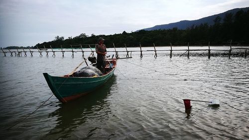 People in boat on river against sky