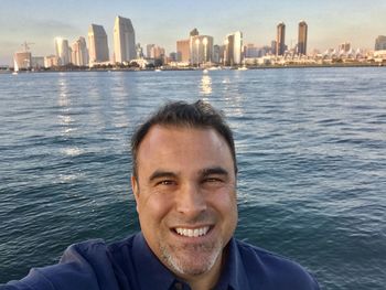 Portrait of smiling man in sea against buildings in city