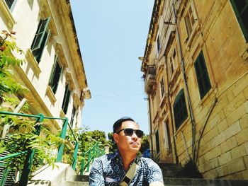 Portrait of man standing by building against sky