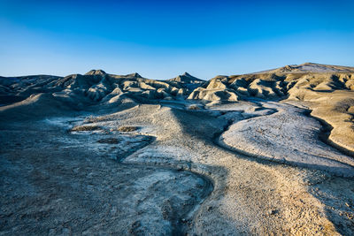 Scenic view of arid landscape against clear blue sky