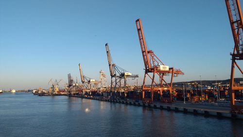 Cranes at commercial dock against clear sky