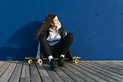 Woman looking away while sitting on wood