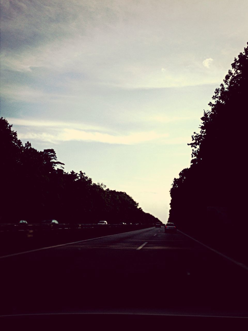 sky, road, transportation, the way forward, tree, silhouette, cloud - sky, car, street, cloud, road marking, built structure, land vehicle, diminishing perspective, architecture, building exterior, vanishing point, outdoors, no people, nature