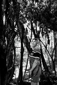 Portrait of young woman standing by tree