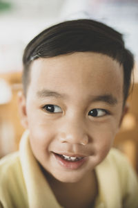 Close-up of smiling boy looking away while sitting indoors
