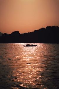 Silhouette boat sailing on sea against clear sky during sunset