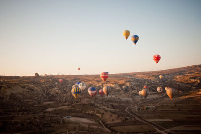 Hot air balloons on field against sky during sunset