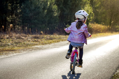 Rear view of boy with bicycle on road