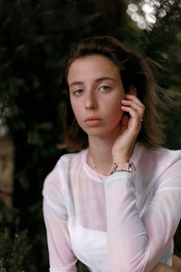 Portrait of young woman against trees