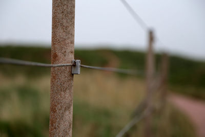 Close-up of barbed wire fence on field