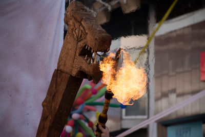 Low angle view of burning hanging on wood against building