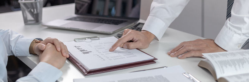 Midsection of real estate agent giving key to customer in office