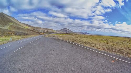 Empty road by mountains against sky