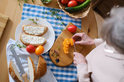 Top view of a senora cutting a tomato for making a healthy sandwich