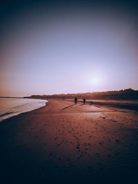 People on beach against sky during sunset