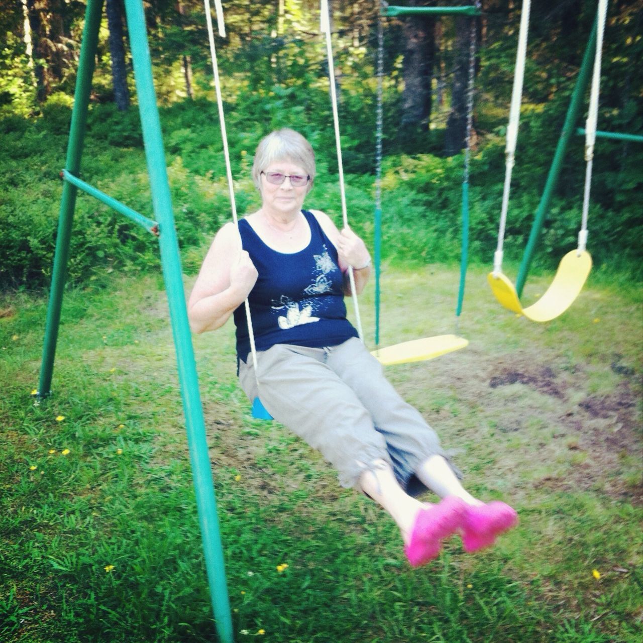 person, grass, casual clothing, full length, lifestyles, childhood, leisure activity, elementary age, happiness, smiling, looking at camera, front view, portrait, green color, park - man made space, tree, standing, swing