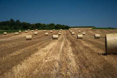 Straw bales on field against clear sky