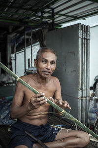 Portrait of shirtless man sitting outdoors