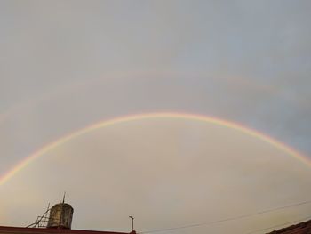 Low angle view of rainbow over building against sky