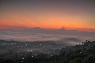 Scenic view of landscape against dramatic sky during sunset