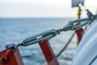 Turn buckle and bulldog clamp holding a life raft on a construction work barge at oil field