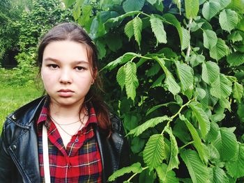 Portrait of young woman standing against plants