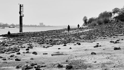 People walking on beach against clear sky