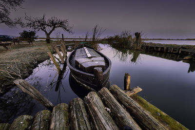 Wooden post by lake against sky